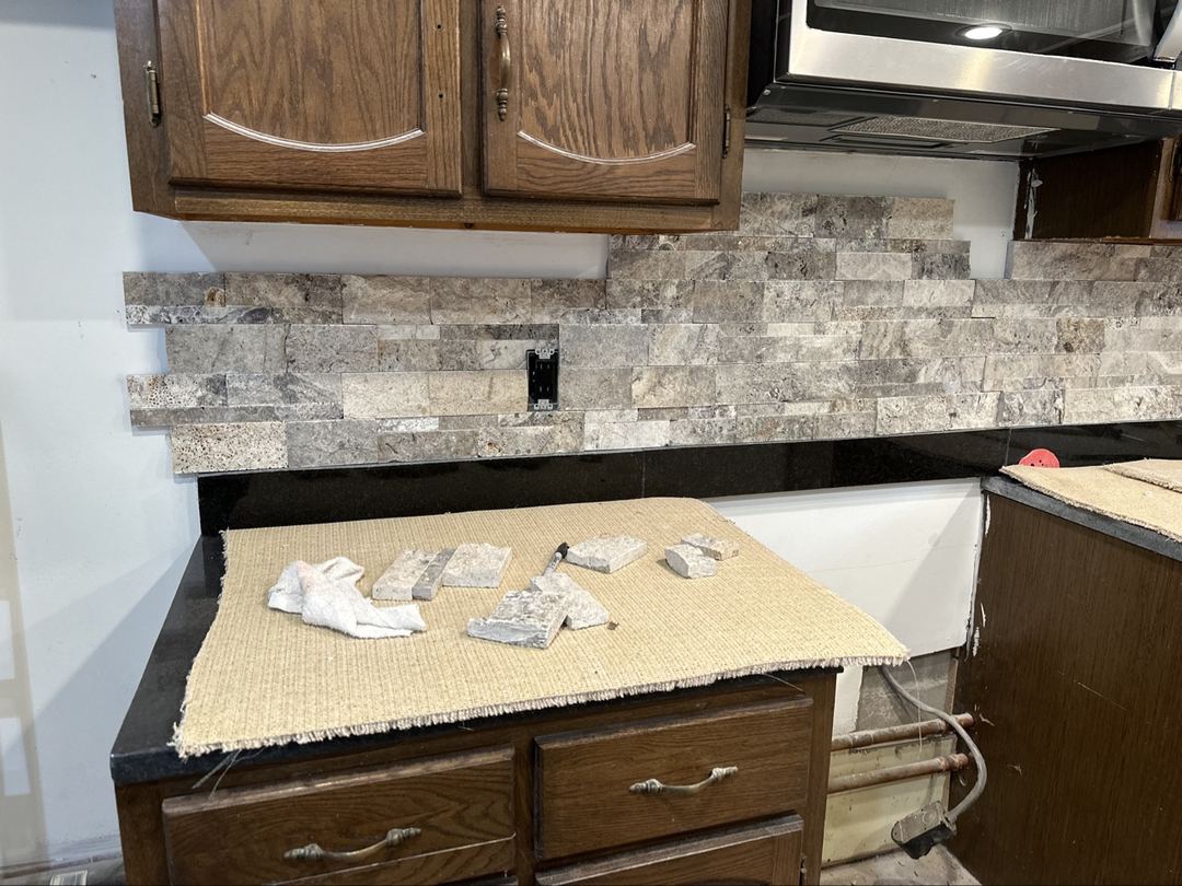 Stacked ledger stone backsplash being installed around kitchen outlets