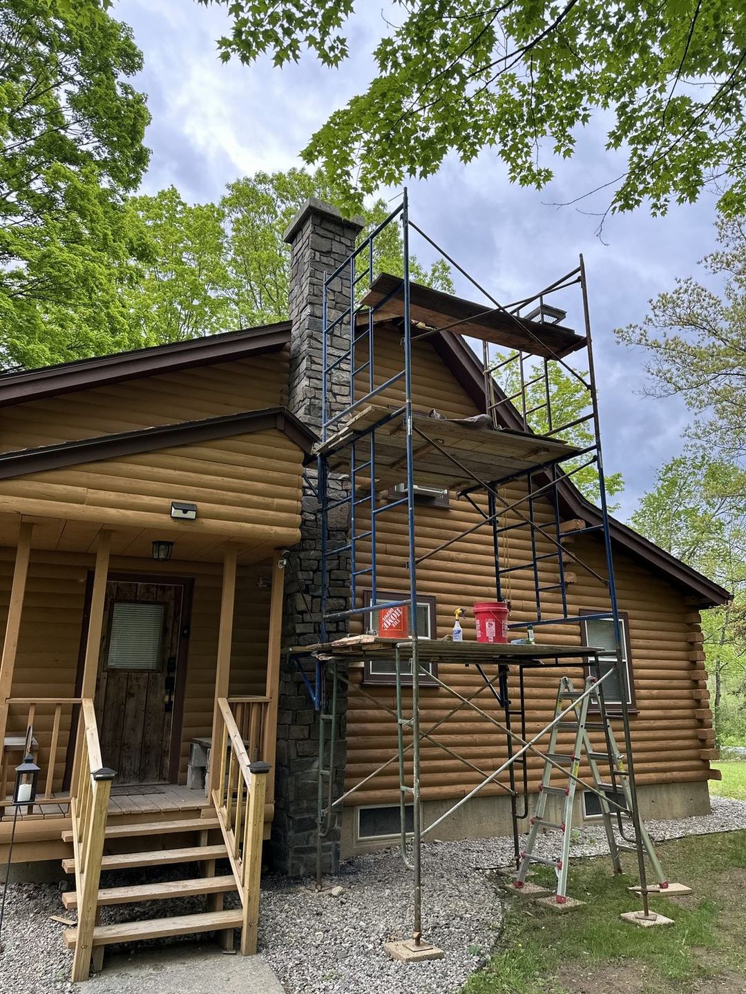 Wide view from the scaffold of the finished stone chimney against the whole cabin